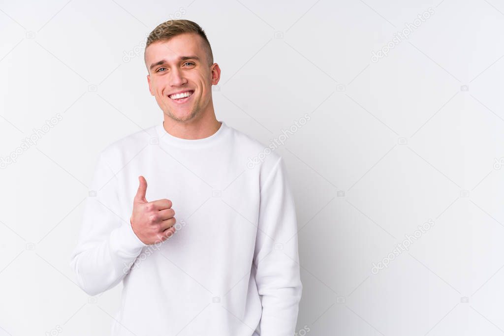 Young caucasian man on white background smiling and raising thumb up