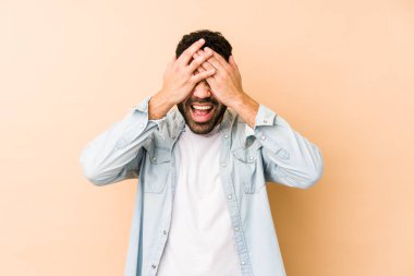 Genç, melez, Arap bir adam izole edilmiş, elleriyle gözlerini kapatmış, gülümseyerek bir sürpriz bekliyor..