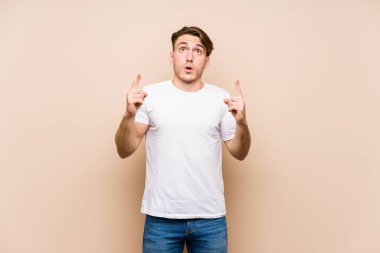 Kafkasyalı genç bir adam yalnız poz verip ağzı açık bir şekilde yukarı işaret ediyor..