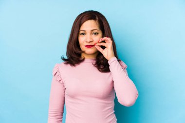 Orta yaşlı Latin bir kadın dudaklarında parmaklarıyla bir sır saklıyor..