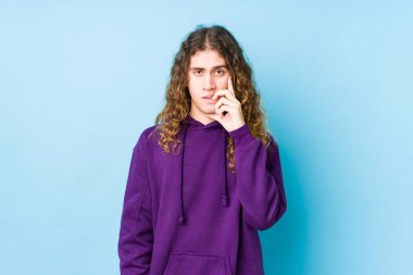 Uzun saçlı adam tırnak yiyor, gergin ve endişeli..