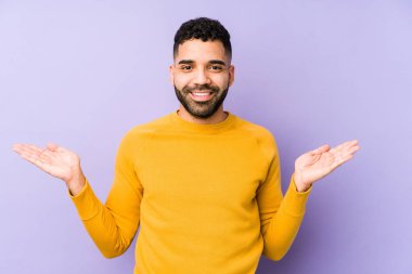 Genç, melez Arap bir adam soyutlanmış, kollarıyla ölçek yapıyor, mutlu ve kendinden emin hissediyor..