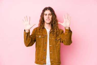 Genç uzun saçlı adam yalnız poz veriyor. 10 numarayı elleriyle gösteriyor..