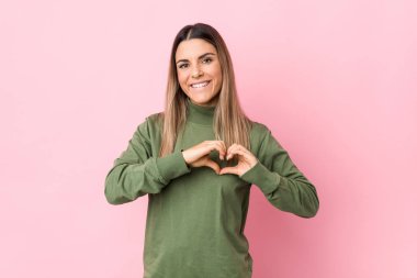 Kafkasyalı genç bir kadın izole edilmiş gülümsüyor ve elleriyle kalp şeklini gösteriyor..