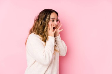 Pembe arka planda poz veren kıvrımlı bir kadın yüksek sesle bağırıyor, gözleri açık ve elleri gergin tutuyor..