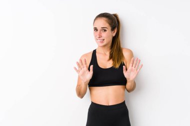 Beyaz arka planda poz veren beyaz tenli kadın iğrenme hareketi gösteren birini reddediyor..