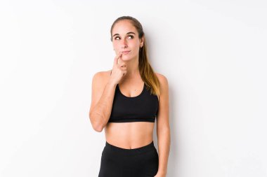 Beyaz arka planda poz veren beyaz tenli kadın şüpheli ve şüpheci bir ifadeyle yana bakıyor..