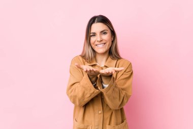 Kafkasyalı genç bir kadın avuçlarıyla bir şey tutarak kameraya sunuyor..