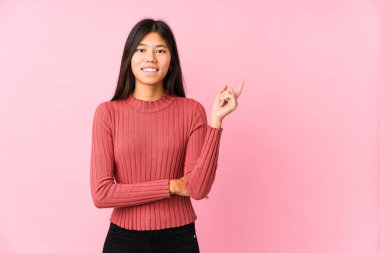 Yalnız poz veren genç Çinli kadın işaret parmağıyla işaret ederek gülümsüyor..