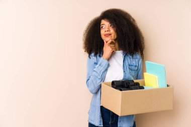Genç afro kadın eve yalnız taşınıyor. Genç afro kadın şüpheli ve şüpheci bir ifadeyle yana bakıyor..
