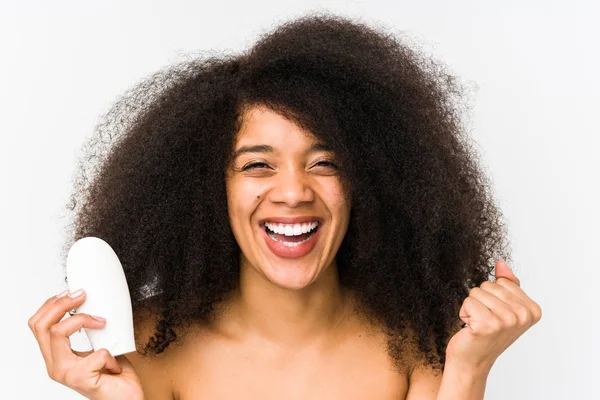 Mujer Afro Joven Sosteniendo Una Crema Hidratante Aislada Animando Despreocupado —  Fotos de Stock