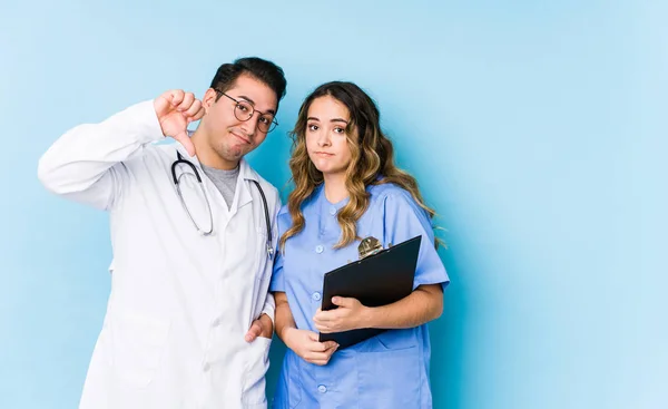 Young Doctor Couple Posing Blue Background Isolated Showing Dislike Gesture — Stock Photo, Image