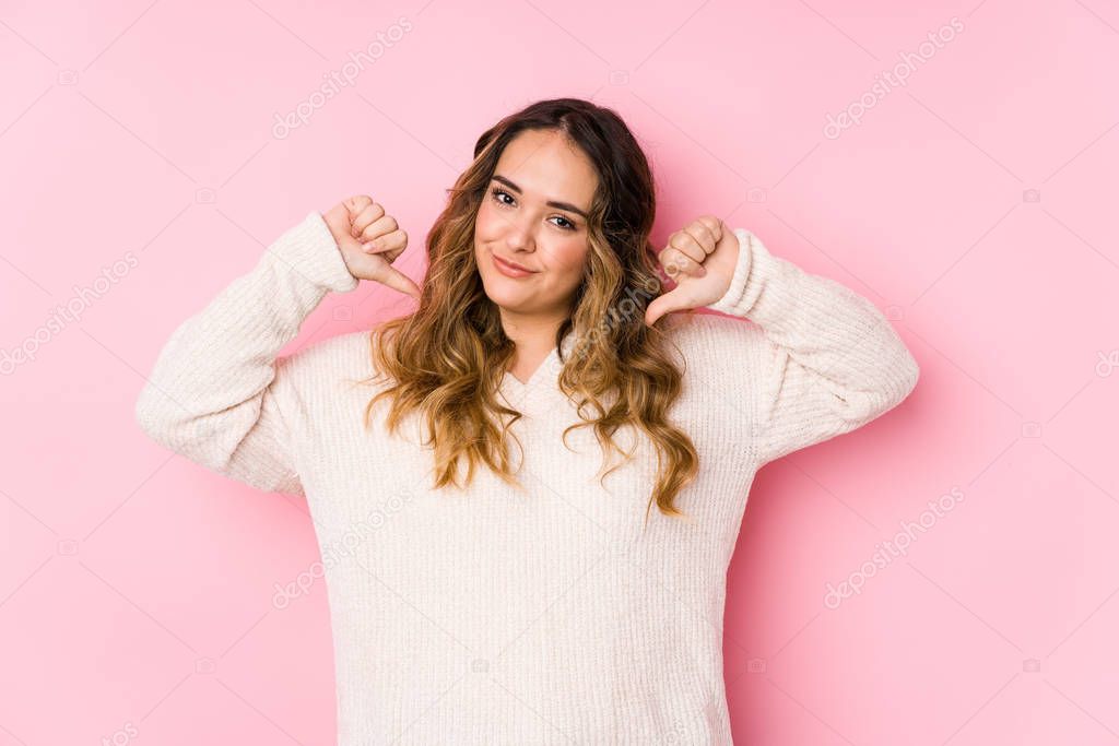 Young curvy woman posing in a pink background isolated feels proud and self confident, example to follow.