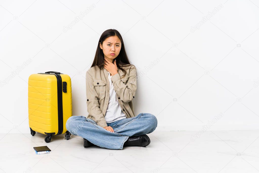 Young chinese traveler woman sitting holding a boarding passes suffers pain in throat due a virus or infection.