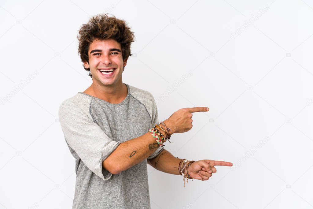 Young caucasian man against a white background isolated excited pointing with forefingers away.
