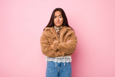 Kısa bir koyun derisi ceket giyen genç Hintli kadın kameraya alaycı bir ifadeyle bakıyor..