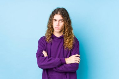 Uzun saçlı adam kameraya bakıp alaycı bir ifadeyle mutsuz poz veriyor..