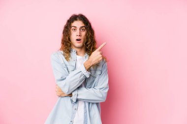 Uzun saçlı adam yanlamasına poz veriyor.