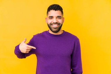 Genç, melez, Arap bir adam tişört fotokopi alanını elle işaret ediyor, gururlu ve kendinden emin.
