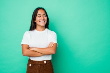 Genç melez Hintli kadın kendini soyutlamış kollarını kavuşturarak gülümsüyor..