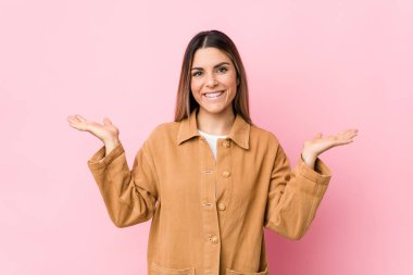 Kafkasyalı genç kadın kollarıyla ölçek yapıyor, mutlu ve kendinden emin..