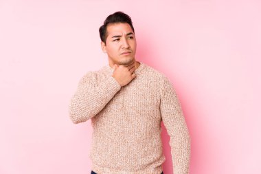 Young curvy man posing in a pink background isolated suffers pain in throat due a virus or infection.