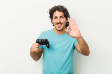 Genç adam elinde bir oyun kumandası tutuyor neşeli ve kendinden emin..