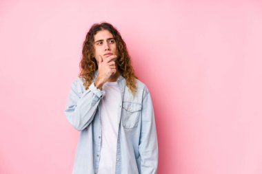 Uzun saçlı adam şüpheli ve şüpheci ifadesiyle yanlamasına poz veriyor..