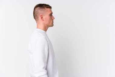 Beyaz arka planda genç beyaz bir adam sola bakıyor, yandan poz veriyor..