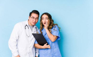 Mavi arka planda poz veren genç doktor çift gizli bir sıcak fren haberinin olduğunu söylüyor.