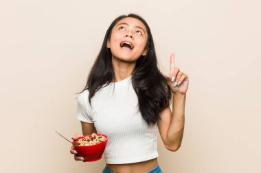 Genç Asyalı kadın elinde mısır gevreği kasesi, ağzı açık bir şekilde yukarı bakıyor..