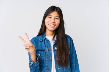 Genç Asyalı kadın neşeli ve kaygısız. Barış sembolünü parmaklarıyla gösteriyor..