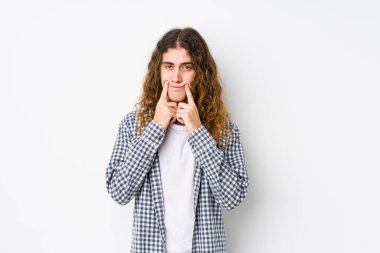 Genç, uzun saçlı adam iki seçenek arasında kuşkuyla poz veriyor..