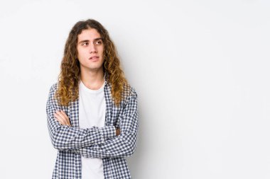 Uzun saçlı, yalnız poz veren, kendine güvenen, kollarını kavuşturmuş genç bir adam..