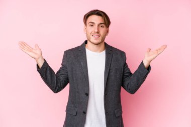 Kafkasyalı genç bir iş adamı yalnız poz veriyor kollarıyla ölçek yapıyor, mutlu ve kendinden emin hissediyor..