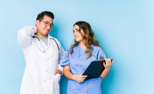 Junges Ärztepaar Posiert Isoliert Vor Blauem Hintergrund Und Leidet Unter — Stockfoto