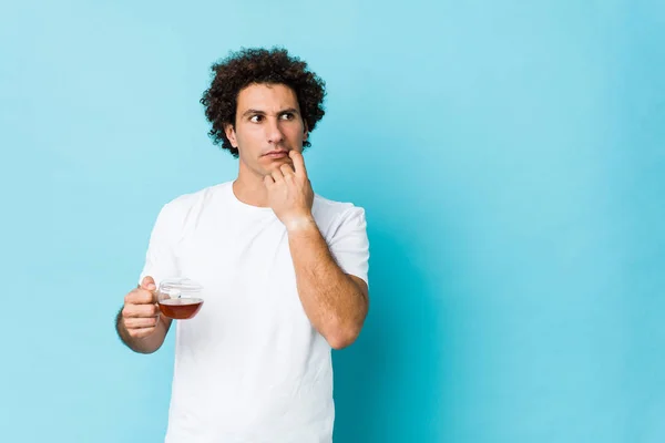 Young Caucasian Curly Man Holding Tea Cup Relaxed Thinking Something — Stock Photo, Image