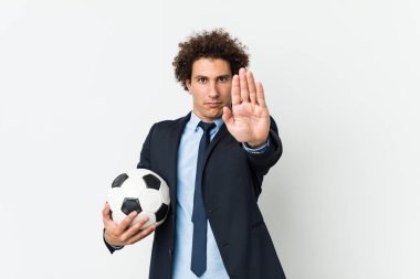 Futbol antrenörü, elinde bir topla dur işareti göstererek seni engelliyor..