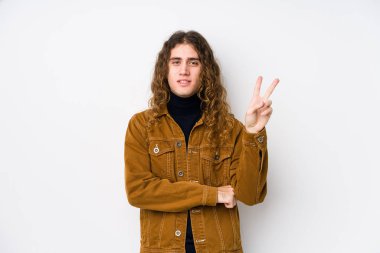 Uzun saçlı adam yalnız poz veriyor. İki numarayı parmaklarıyla gösteriyor..