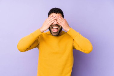 Genç, melez, Arap bir adam izole edilmiş, elleriyle gözlerini kapatmış, gülümseyerek bir sürpriz bekliyor..