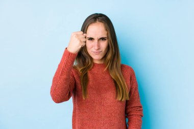 Genç beyaz kadın yalnız poz veriyor kameraya yumruk gösteriyor, agresif yüz ifadesi var..