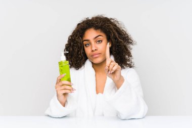 Genç Afrikalı Amerikalı bir kadın, elinde bir numaralı parmağını gösteren bir aloe vera tutuyor..