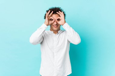 Genç, kıvırcık, olgun bir adam zarif bir gömlek giyiyor ve gözlerinin üzerinde 