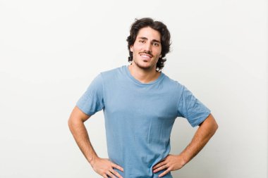 Beyaz bir geçmişi olan genç ve yakışıklı bir adam ellerini kalçasında tutuyor..