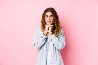 Yalnız poz veren uzun saçlı adam ellerini çenesinin altında tutuyor ve mutlu bir şekilde yan tarafa bakıyor..