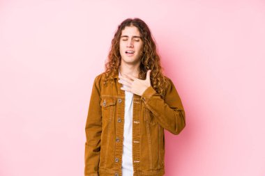 Genç, uzun saçlı, yalnız poz veren adam kahkahalar atıyor. Elini göğsünde tutuyor..