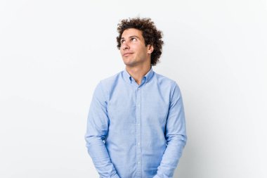 Genç, kıvırcık, olgun bir adam zarif bir gömlek giyiyor. Amaçlarına ve amaçlarına ulaşmayı hayal ediyor.