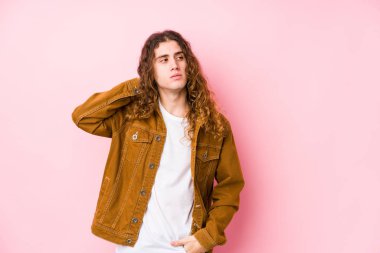 Genç, uzun saçlı adam yalnız poz veriyor. Kafasının arkasına dokunuyor, düşünüyor ve bir seçim yapıyor..