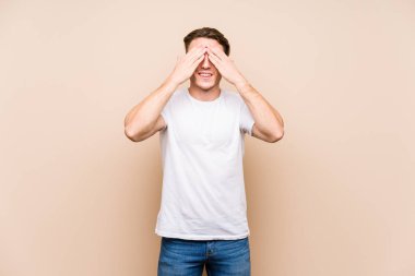 Kafkasyalı genç adam yalnız poz veriyor. Elleriyle gözlerini kapatıyor. Gülümsüyor ve bir sürpriz bekliyor..