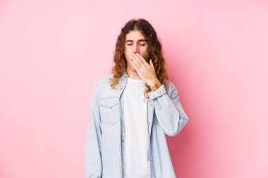 Uzun saçlı adam tek başına esniyor. Ağzı eliyle kapatan yorgun bir hareket sergiliyor..